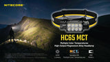 NITECORE HC65 MCT high-output magnesium alloy headlamp shown on a black headband with yellow trim, set against a night mountain hiking scene. The product is highlighted with text and feature icons for 2000 lumens, MCT multiple color temperatures, and 258 meters beam throw.